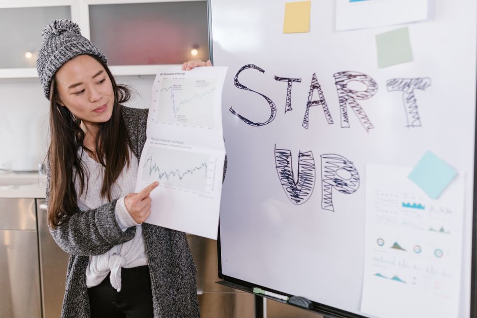 Asian woman presenting business growth charts during a startup pitch indoors.